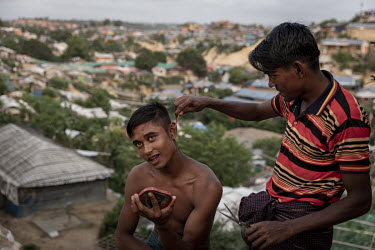 A young man cuts his friend's hair at the Hakimpara Rohingya refugee camp.
