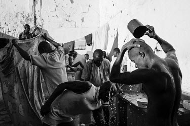 A prisoner washes his hair while behind others are washing clothes outside at Marofoto Prison (known to inmates as Marseilles).  The crowded facility holds on average 650 prisoners in an institution...