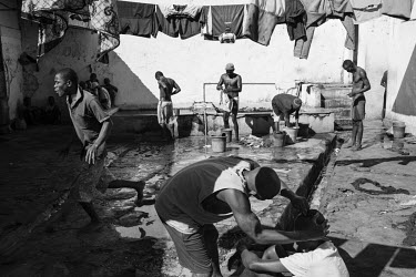 A prisoner has his hair cut while behind them others are washing clothes outside at Marofoto Prison (known to inmates as Marseilles).  The crowded facility holds on average 650 prisoners in an insti...