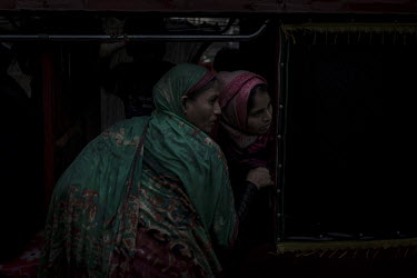 Two Rohingya women wait for a bus to depart in the middle of the night.   For some Rohingya refugees, the bus stations on the outskirts of Cox's Bazar town are where they start a risky and sometimes...