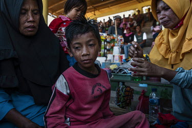 Child jockey Imam Dudu (8) weeps as he regains consciousness while his mother Tiara (36) prepares a drink of warm sugar water for him, after a fall in a preliminary round of the 'Regional Police Chief...
