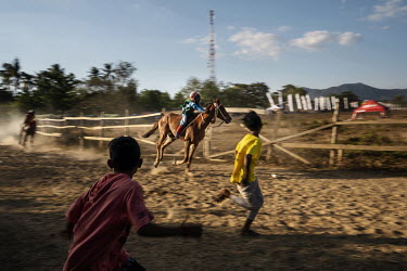 Stable boys race to catch a horse ridden by a child jockey after it crossed the finishing line during a preliminary round of the 'Regional Police Chief's Cup 2019'.  Racing is deeply rooted in the isl...