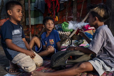 Child jockey Imam Dudu (8, centre) watches a friend and fellow child jockey vaping on an e-cigarette at their camp in the evening after racing in the 'Regional Police Chief's Cup 2019'.Racing is deepl...