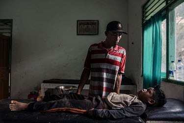 Abdul Gani (35) stands over his injured nephew Firmansyah (8) in a clinic near the racecourse where Firmansyah fell during a race in the preliminary stages of the 'Regional Police Chief's Cup 2019'.Ra...