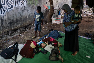 Neighbours check on child jockey Firmansyah (8) as he lies injured following a fall during a race in the preliminary stages of the 'Regional Police Chief's Cup 2019'.  Racing is deeply rooted in the i...