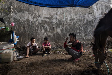 Child jockey Firmansyah (8, second from left) eats his breakfast along with stable boys from his village at their camp near the racecourse where they are based during the preliminary stages of the 'Re...