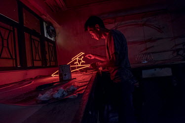 Choy Chun Wa (52) applies the final touches to part of a neon sign, painting a layer of black lacquer over certain sections to block them out, in Master Wong's workshop in Mong Kok. Wa and Master Wong...