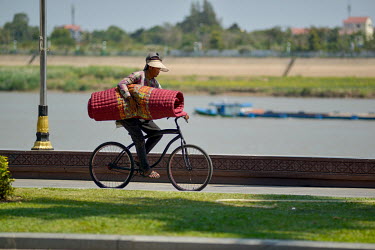 A carpet seller cycling along the embankment for the Tonle Sap river.