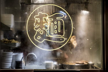A man stirs a pot of stew behind a neon sign in the window of the Starry Kitchen on Portland Street.
