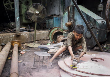 A child labourer using an angle grinder, without safety equipment, in a workshop producing parts for the ship building industry. Child labour in Bangladesh is common, with 4.8 million or 12.6% of chil...