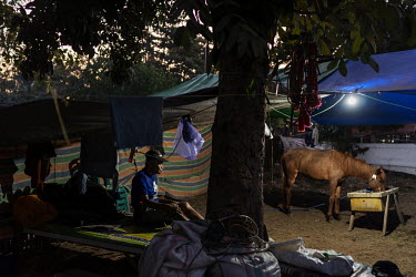 A race horse trainer rests on a camp bed after feeding the horses he looks after in a camp, beside the racecourse, where they are staying during the 'Regional Police Chief Cup 2019'.Racing is deeply r...