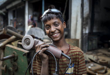 A child labourer in a workshop producing parts for the ship building industry. Child labour in Bangladesh is common, with 4.8 million or 12.6% of children aged 5 to 14 in the workforce.