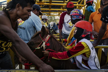 Child jockeys and trainers wait in the starting gates ahead of a preliminary round of the 'Regional Police Chief Cup 2019'.  Racing is deeply rooted in the island's culture but the use of children,...