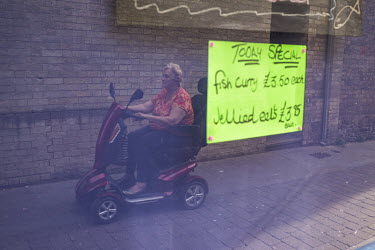 A woman riding on a mobility scooter passes the window of a fishmongers advertising Jellied Eels and fish curry.   In the 2016 referendum on Britain's position within the EU, the Boston district produ...