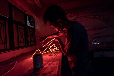 Choy Chun Wa, 52, applies the final touches to a part of a neon sign - painting a layer of black lacquer over certain sections to block them out - in Master Wong's workshop in Mong Kok, Hong Kong. The...