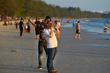 Chinese tourists taking photos at sunset on Ou Chheuteal Beach.