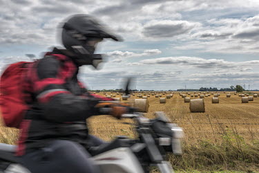 A motor scooter rider passing a field dotted with rolls after the harvest near the hamlet of Tongue End near South Holland.  In the 2016 referendum on Britain's membership of the EU, the South Holland...