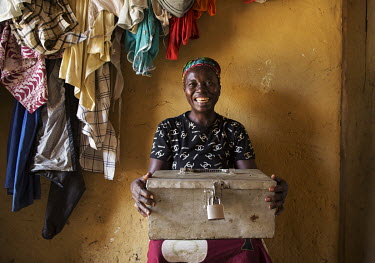 Messah Brewah cares for one of the metal savings boxes used by women members of a savings and loan scheme in the village of Bumbeh Pejeh.