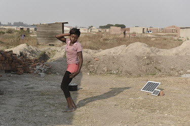 A young girl dances to music on a radio in her family's yard. The people living in her town of Chitungwiza only receive electricity from 8 to 9 in the evening for much of the year, and those who can a...