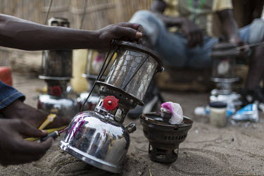 A fisherman marks an oil lamp so it can be identified as his. The lamps are used at night to attract small fish by fishermen on Lake Mweru.  At around five o'clock in the afternoon, fishermen prepare...