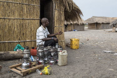 A fisherman sits beside his oil lamps all marked so they can be identified as his when they are left out on the lake. The lamps are used at night to attract small fish by fishermen on Lake Mweru.  At...