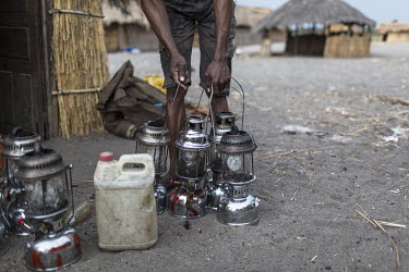 A fisherman with his oil lamps, all marked so they can be identified as his when they are left out on the lake. The lamps are used at night to attract small fish by fishermen on Lake Mweru.  At around...