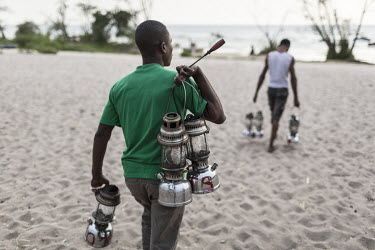 A fisherman carries his oil lamps to th elake shore. They are all marked so they can be identified as his when they are left out on the lake. The lamps are used at night to attract small fish by fishe...