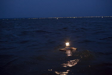 A fisherman's fish trap floating on Lake Mweru. The traps use light to attract small fish.  At around five o'clock in the afternoon, fishermen prepare to go out on Lake Mweru. They use floating oil la...