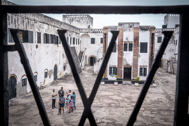 A group of tourists in the courtyard during a tour of Elmina Fort.