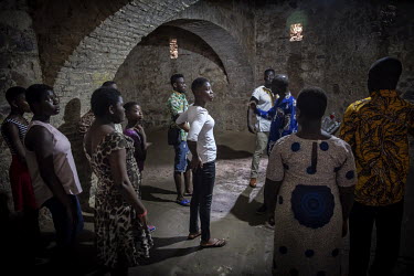Alex, a tour guide, tells his group the history of the Elmina Fort while stood in the dungeons where the slaves were kept before being taken by ship across the Atlantic Ocean.