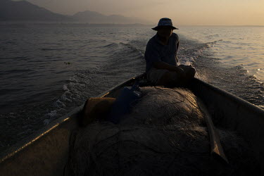 A fisherman, who prefers to remain anonymous due to fear of being criminalised, rides his boat at dawn on Lake Izabal.