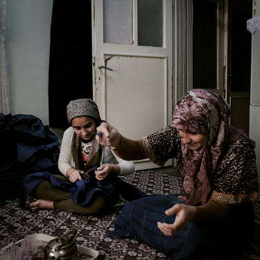 Syrian refugee Dalal Eissa (13) with her mother Ayesha in their family's small apartment where they spend most days cutting cotton threads from pairs of jeans which are made in a nearby factory. The m...