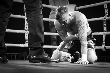An injured fighter on his knees in the ring at the Ultimate Bare-Knuckle boxing competition at Manchester's Bowlers Exhibition Centre, Old Trafford.