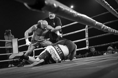 Luka Curri (L) stands over the prostrate Martyn Cavna during their bout, won by Curri, at the Ultimate Bare-Knuckle boxing competition at Manchester's Bowlers Exhibition Centre, Old Trafford.