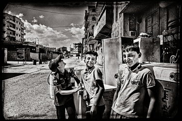 Boys playing in the destroyed streets beside a store of refrigerators waiting to be repaired.