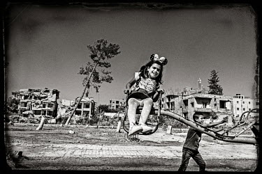 Children enjoy a ride in a playground in the destroyed city center. Before the liberation the playground was used by ISIS to stage mass executions.
