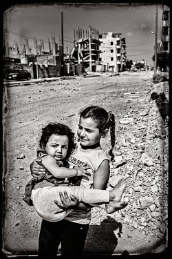 Two sisters walking through the war damaged streets.