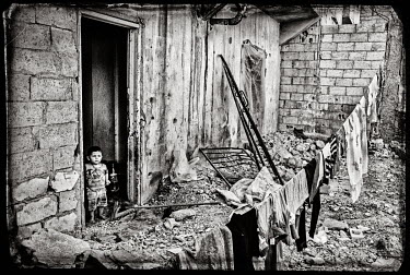 A boy stands in the doorway of a destroyed appartment.