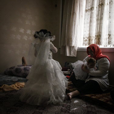 Yesim Ger, a Turkish resident of the district of Gulen, helps as two young Syrian girls dress in the outfits they will wear to a secret Syrian wedding near Gaziantep. Weddings of young Syrian girls wh...