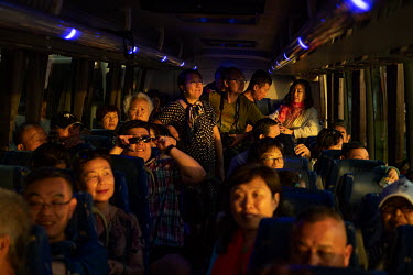A group of Chinese tourists on a bus tour, arrive below Sydney's Harbour Bridge shortly before Sunset.
