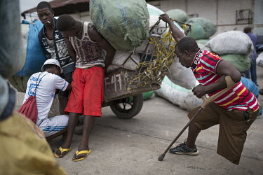 A disabled man with sacks of imported goods at Onatra port. As disabled people pay less import fees savvy traders use them to import cargo cheaply from Congo Brazzaville. As soon as the goods leave th...