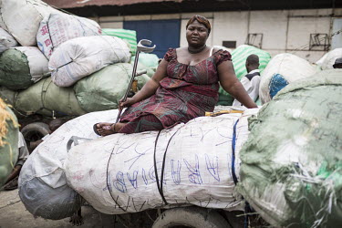 A disabled woman sitting on sacks of imported goods at Onatra port. As disabled people pay less import fees savvy traders use them to import cargo cheaply from Congo Brazzaville. As soon as the goods...
