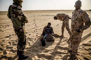 Members of a Nigerien military patrol careful look through Aghali Ahmet's possessions to make sure he is not terrorist. Ahmet says the car in which he was travelling to Libya broke down and he was aba...