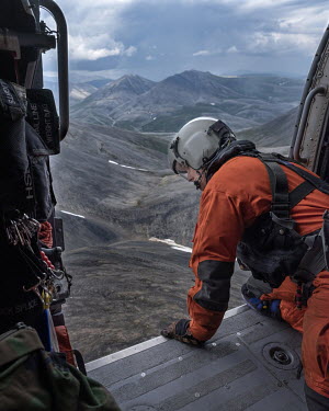 Jasun, a flight mechanic and winch-man with a coastguard team, looks out from a Jay Hawk helicopter as it flies over the mountains north-east of Kotzebue during a search and rescue exercise.