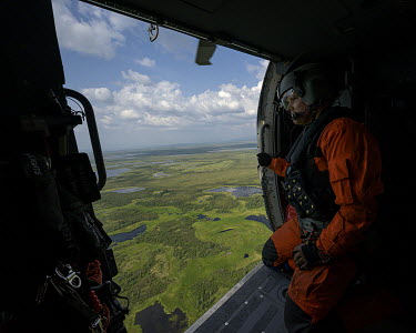 Jasun, a flight mechanic and winch-man with a coastguard team, looks out from a Jay Hawk helicopter as it flies over the land near Kotzebue during a search and rescue exercise.