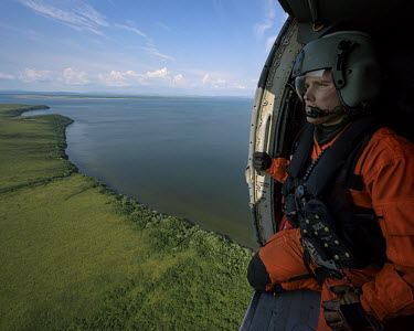Jasun, a flight mechanic and winch-man with a coastguard team, looks out from a Jay Hawk helicopter as it flies over the land near Kotzebue during a search and rescue exercise.