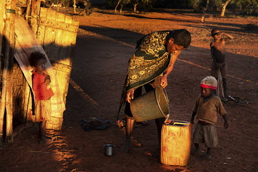 A woman fills a jerry can with muddy water.
