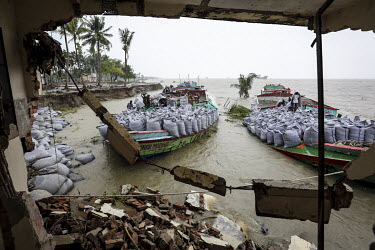 Barges deliver sand filled sacks to shore up the crumbling banks of the Meghna River which has burst its banks during heavy rains devouring land and buildings.