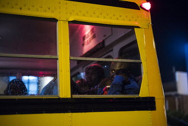 Detained asylum seekers look out from the back of a bus they are being transported in to a processing centre at the Canadian border.