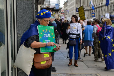 A woman checks her phone as people march in central London at an anti-Brexit Rally on so-called 'Super Saturday', 19th October 2019, when the decision whether to accept Boris Johnson's Brexit deal mad...
